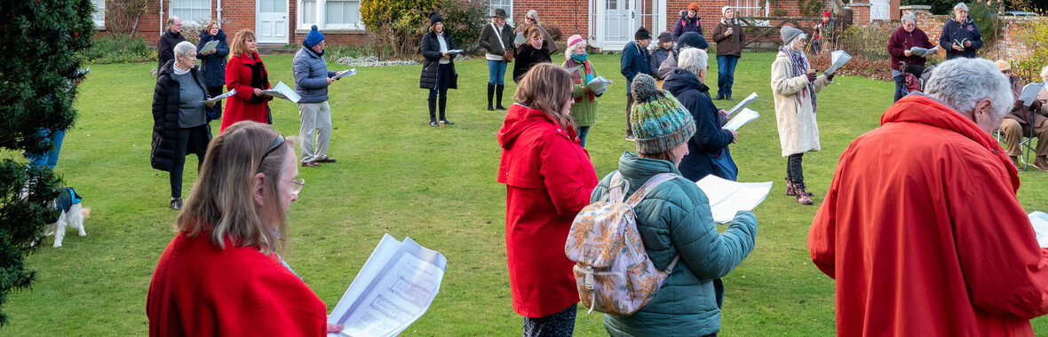 People singing Christmas carols in front of The Red House
