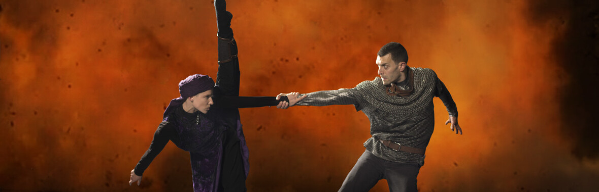Male and female dancers in a battel dance, with orange smoke behind