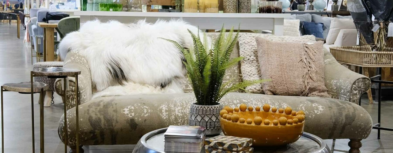 A sofa with coffee table in front with plant sitting on table